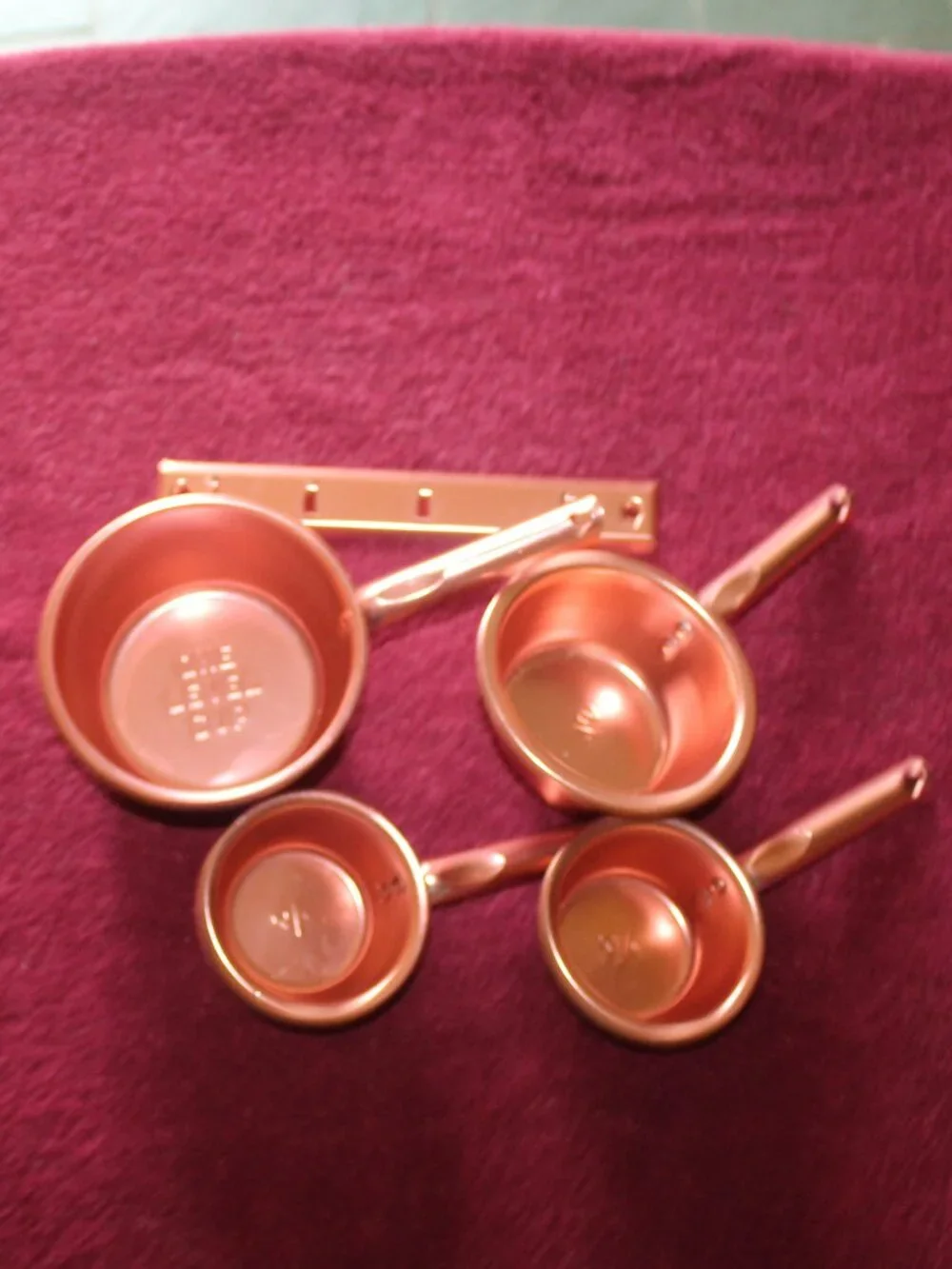 4-piece copper colored metal measuring cups, complete with a matching hanger